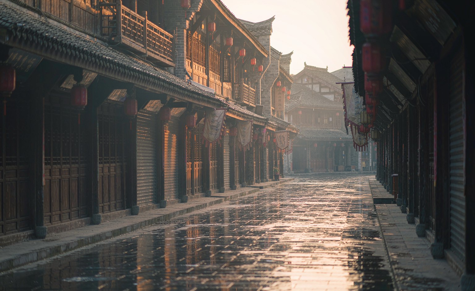 An empty stone street of traditional shopfronts and red lanterns at Ciqikou in early morning light